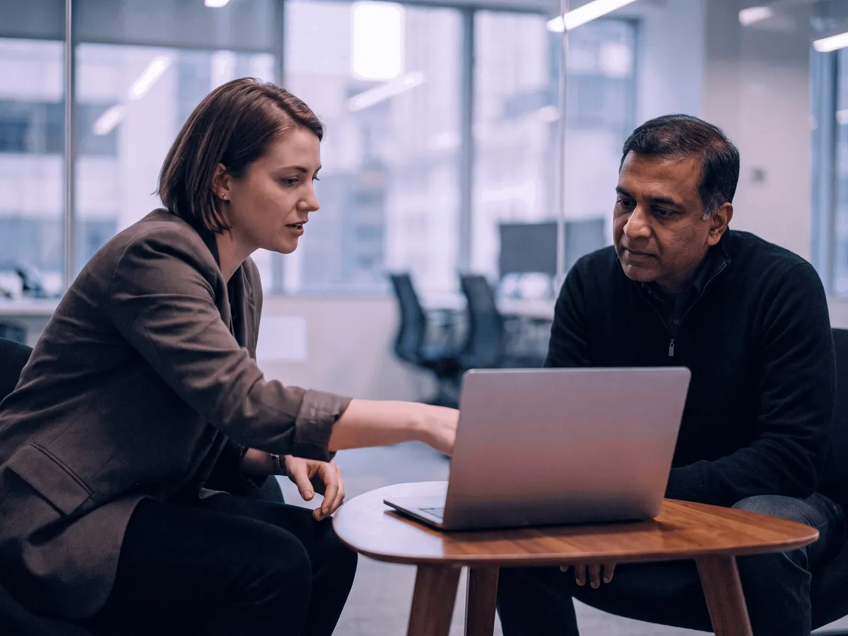 A bookkeeper and a business owner going over his books on a laptop